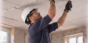 Ouvrier travaillant au plafond, les deux bras levés au-dessus des épaules, tête en arrière